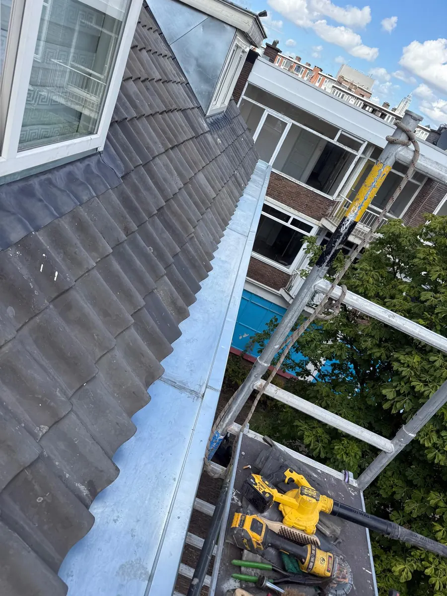 Metalen goot langs een pannendak met dakkapel